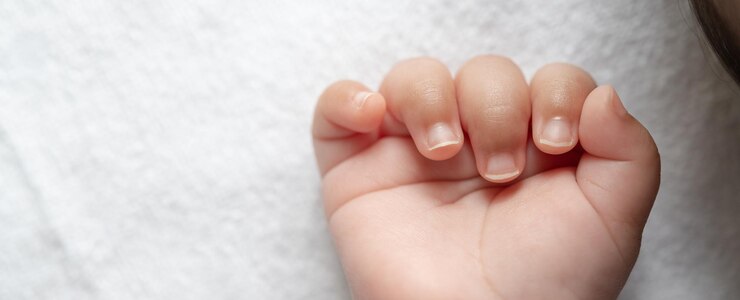 Tangan bayi baru lahir di tempat tidur putih Fokus selektif