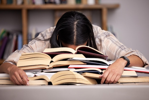 Tanto da studiare. Inquadratura ritagliata di una giovane studentessa irriconoscibile che sembra esausta mentre studia in biblioteca.