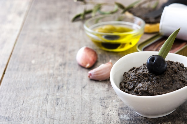 Tapenade di olive nere con acciughe, aglio e olio d'oliva sulla tavola di legno