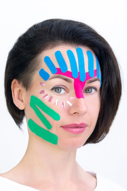 Taping facciale, primo piano del viso di una ragazza con nastro cosmetico antirughe. Taping estetico viso.