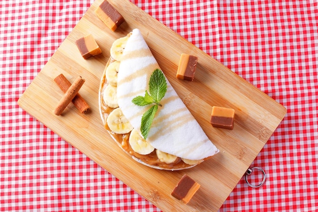 Tapioca fatta in casa o beiju ripieni di banana e latte condensato o caramello al malto su tavola di legno rustico