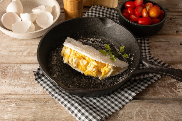 Tapioca Pancake con uova Cibo di manioca brasiliano in vista anteriore all'interno di una padella in acciaio nero