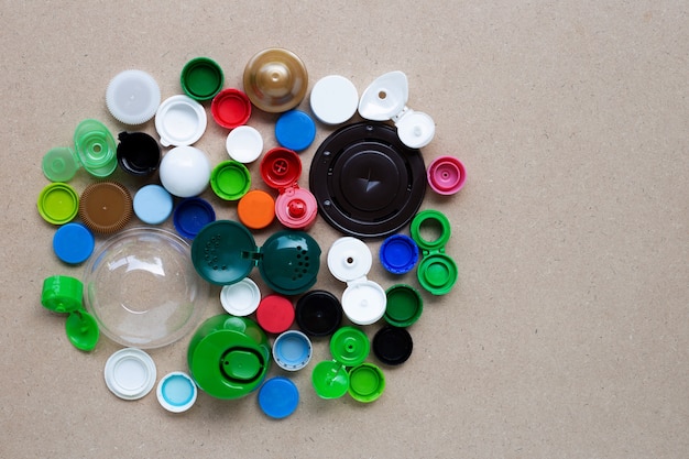 Tappi di bottiglia di plastica colorati e coperchio in vetro di plastica su sfondo di compensato. Vista dall'alto