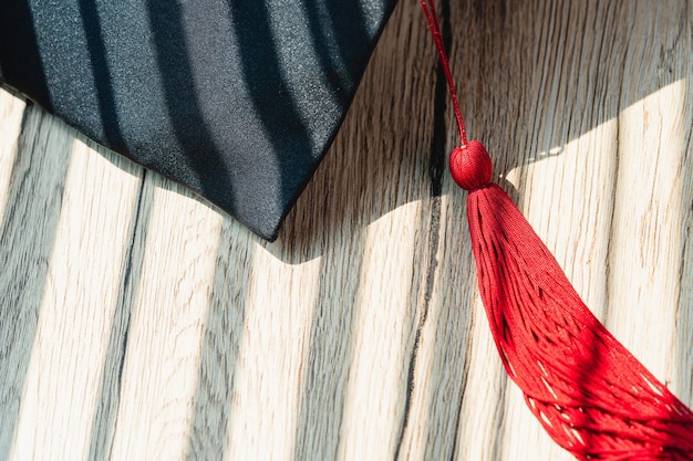 Tappo di graduazione nero Livello universitario posto su una graduazione di concetto di tavolo di legno