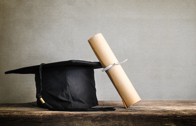 Tappo di laurea, cappello con carta di laurea sul tavolo di legno Vuoto