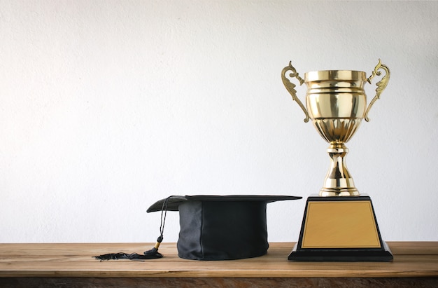 Tappo di laurea con il trofeo d&#39;oro campione sul tavolo di legno