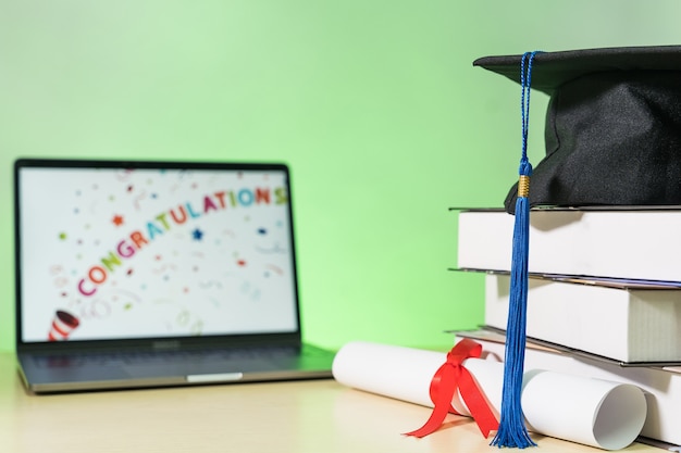 Tappo di laurea con libri e certificato di diploma isolato su tavola di legno