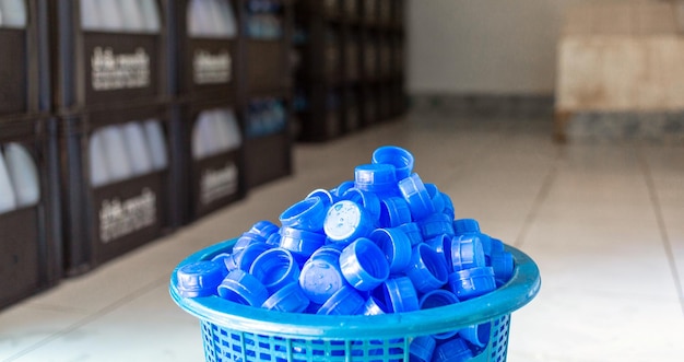 Tappo per bottiglia d'acqua in plastica blu Molte pile insieme in un cesto di plastica nella fabbrica di acqua potabile