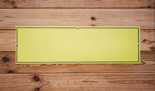Targhetta gialla vuota sulla tavola di legno