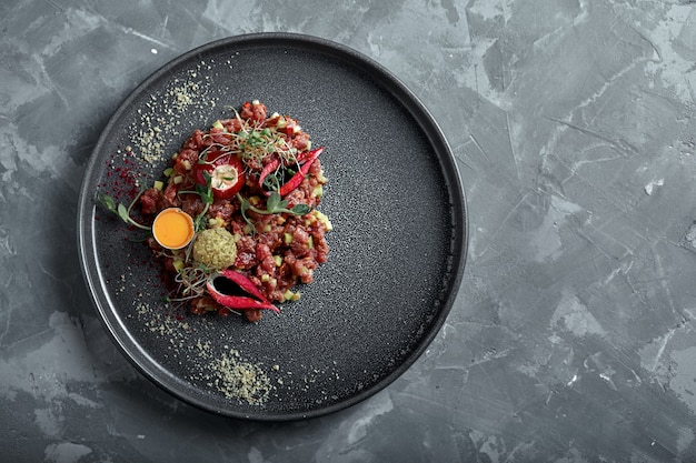 Tartara di manzo con tuorlo d'uovo su una superficie grigia, vista dall'alto, spazio di copia del primo piano