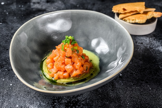 Tartare di salmone affumicato e avocado. Sfondo nero. Vista dall'alto