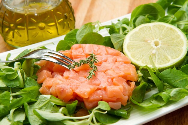 tartare di salmone con insalata fresca e fetta di limone