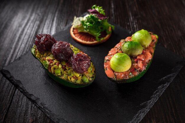 Tartare di salmone e insalata di avocado su sfondo nero. La presentazione originale dei piatti dello chef