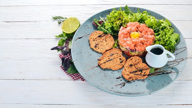 Tartaro con salmone e avocado su sfondo di legno Vista dall'alto Spazio di copia