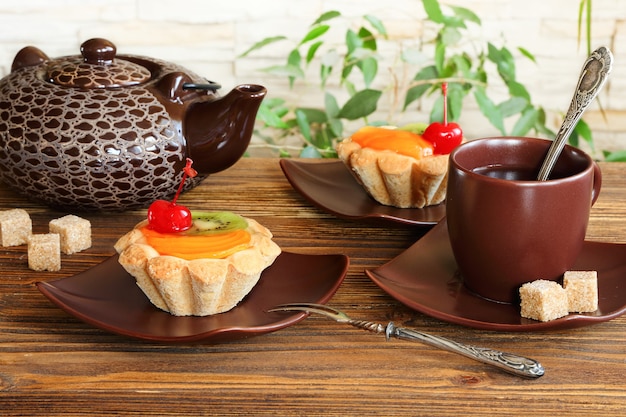 Tartellette con frutta e tè su un tavolo di legno