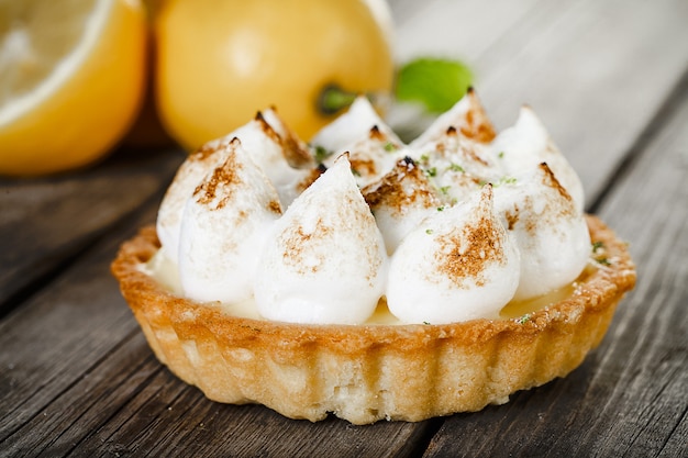 Tartellette di meringa al limone saporite con menta sulla vecchia tavola di legno