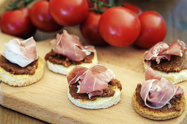 tartine con carne secca, salsa di pomodori secchi su una tavola di legno