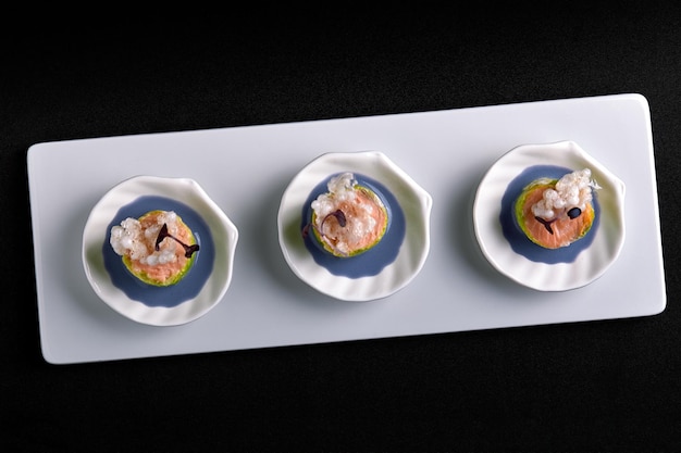 Tartine di salmone al forno con salsa, in piccoli piattini bianchi, concept catering food.