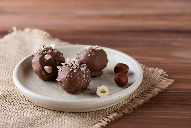 Tartufi al cioccolato con nocciole su tavola di legno marrone zucchero da tavola senza glutine e lattosio vegan