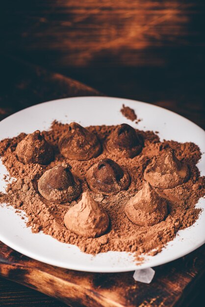 Tartufi al cioccolato fatti in casa ricoperti di cacao in polvere su piatto bianco