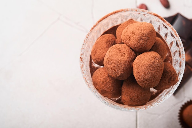 Tartufi al cioccolato Tartufi al cioccolato fatti in casa con cacao in polvere su vetro su sfondo vecchio tavolo piastrellato incrinato Gustose caramelle al tartufo al cioccolato dolce Concetto di San Valentino e festa della mamma