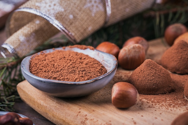 Tartufi di cioccolato fatti in casa, noci, mandorle e cacao in polvere su tagliere di legno. Decorazione per le vacanze invernali.