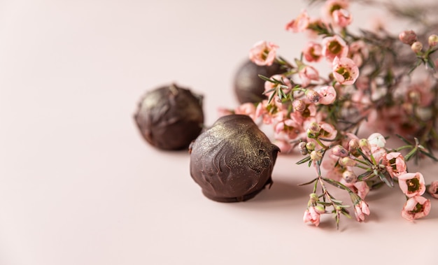 Tartufi di cioccolato su una superficie rosa decorata con fiori rosa