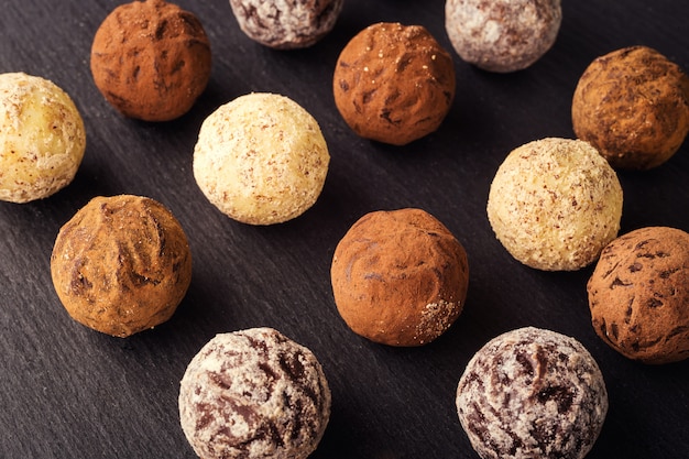 Tartufo al cioccolato, Caramelle al cioccolato al tartufo con cacao in polvere. Collezione di caramelle al cioccolato. Tartufi al cioccolato assortiti con cacao in polvere, cocco e nocciole tritate su un piatto da dessert.