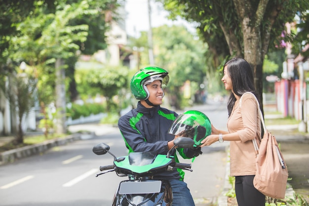 Tassista commerciale del motociclo che dà casco al suo cliente