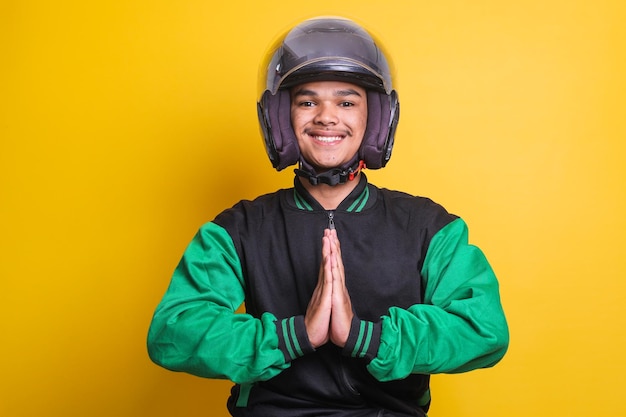 Tassista online asiatico che indossa giacca verde e casco sorridendo e mettendo le mani in segno di saluto o fo