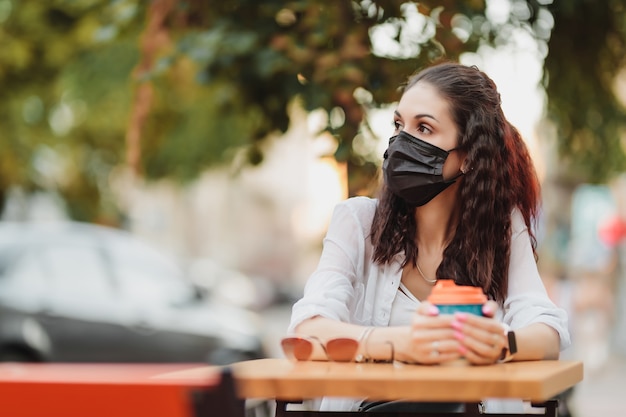 Tasso di quarantena in un bar, una giovane donna con una maschera nera. Foto di alta qualità