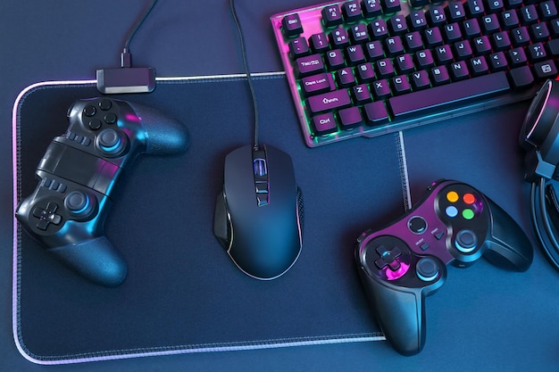 Tastiera RGB del mouse del computer e controller di gioco su sfondo nero vista superiore