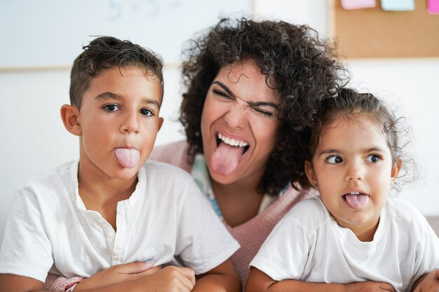 Tata e bambini che fanno l'espressione del viso divertente sulla macchina fotografica - Concetto di asilo nido e felicità