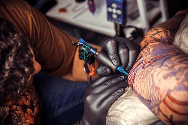 Tatuatore al lavoro nello studio del tatuaggio./Il tatuatore professionista crea il tatuaggio nel negozio di tatuaggi.