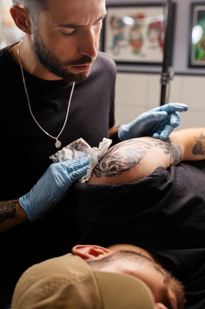 Tatuatore al lavoro vista laterale