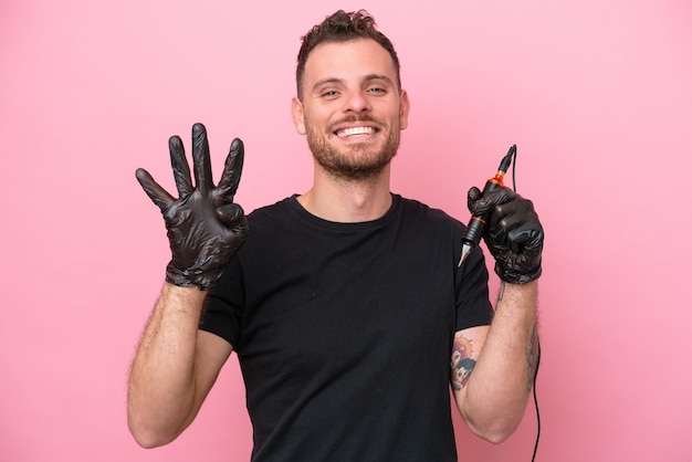 Tatuatore brasiliano uomo isolato su sfondo rosa felice e contando quattro con le dita