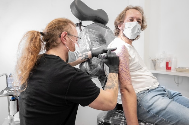 Tatuatore che fa tatuaggio in studio Fotografia di alta qualità