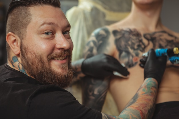 Tatuatore professionista che fa un nuovo tatuaggio per il suo cliente