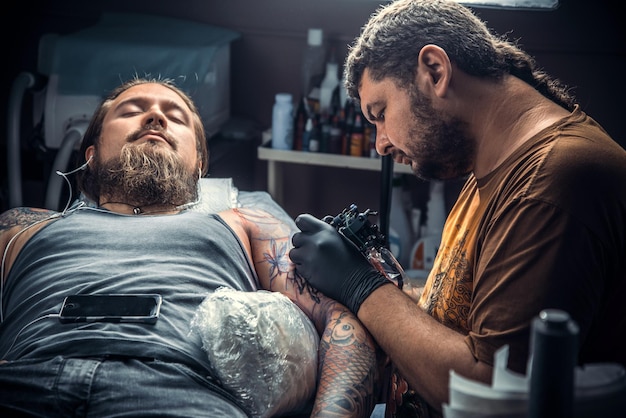 Tatuatore professionista che posa nello studio del tatuaggioTatuatore professionista lavora nel salone del tatuaggio