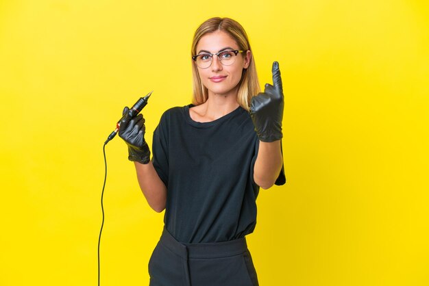 Tatuatore uruguaiano donna isolata su sfondo giallo che fa il gesto in arrivo