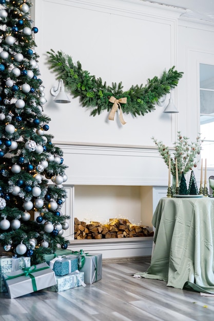 Tavola apparecchiata per la cena di Natale o Capodanno con decorazioni di candele tovaglia e tovaglioli sullo sfondo di un albero di Natale in un appartamento