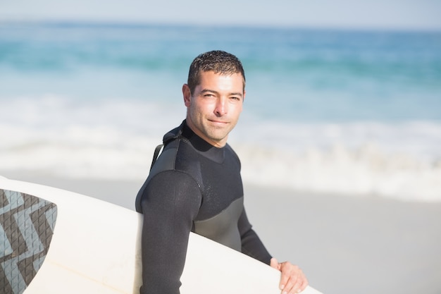 Tavola da surf della holding dell'uomo sulla spiaggia