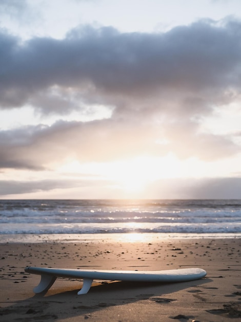 Tavola da surf sdraiato sulla spiaggia e l'alba in un cielo nuvoloso