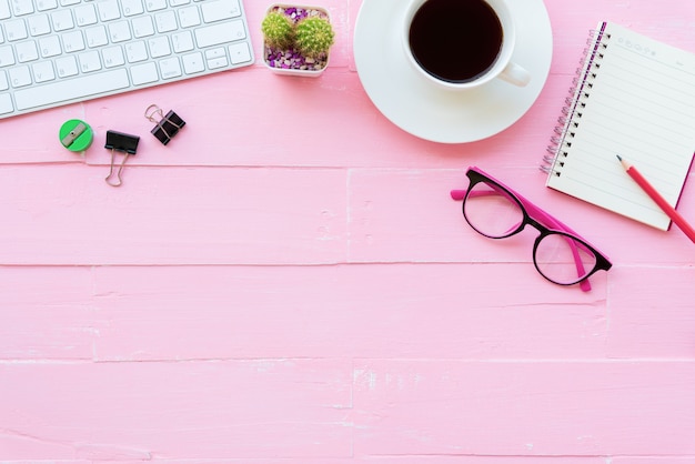 Tavola dell&#39;ufficio di vista superiore con l&#39;area di lavoro e gli accessori dell&#39;ufficio su fondo di legno rosa.