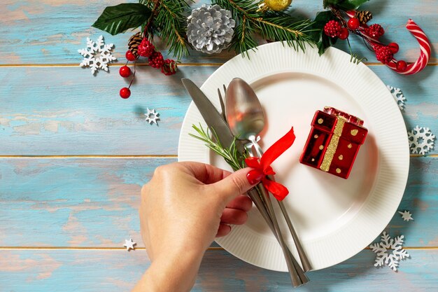 Tavola delle decorazioni natalizie La mano femminile serve il piatto bianco del tavolo festivo presente