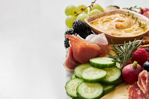 Tavola di formaggio con hummus, frutta e verdura su uno sfondo bianco