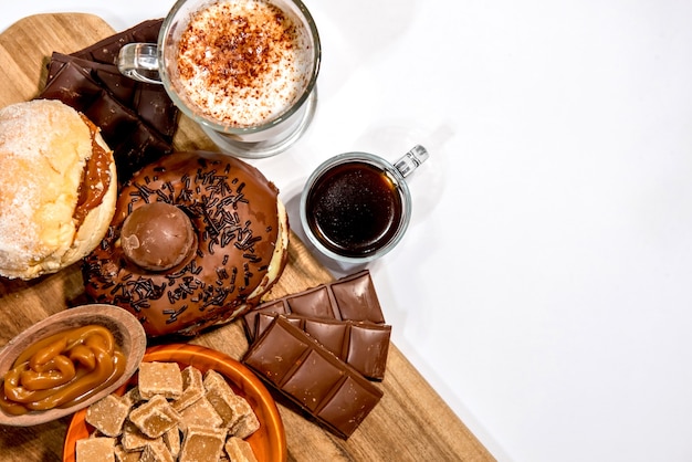 Tavola di legno con ciambelle, cioccolato, caffè e moccha. Vista dall'alto.