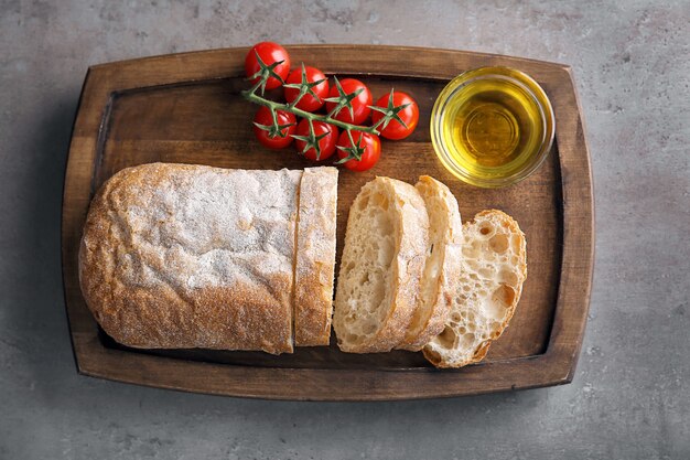 Tavola di legno con olio d'oliva, pane fresco e pomodori sul tavolo