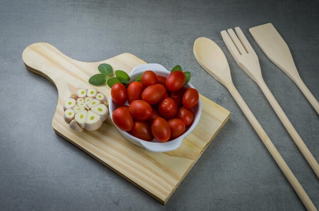 Tavola di legno con pomodorini su sfondo grigio. sfondo culinario.