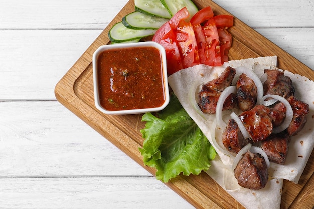 Tavola di legno con shish kebab e salsa sulla vista del tavolo